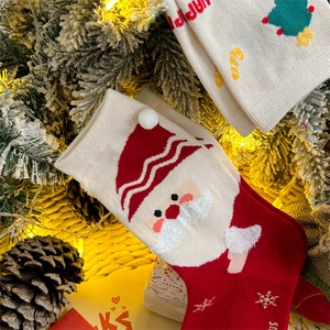 Detail of Christmas crew socks featuring Santa Claus patterns and fuzzy plush pom-poms
