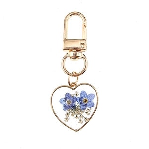 Handmade heart-shaped resin keychain featuring real blue dried flowers and gold metal frame