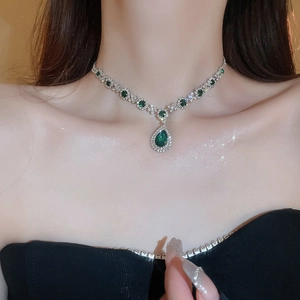 Detailed close-up of a silver necklace with teardrop green crystals and sparkling zircons