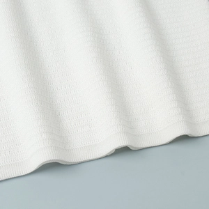 Macro detail of white knitted fabric with fine horizontal texture and ribbed hem edge
