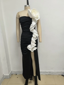 Detail of black strapless evening dress featuring large white 3D floral ruffles and pleats