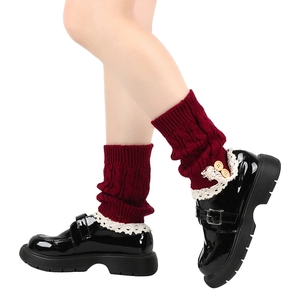Detail of red cable-knit leg warmer with beige lace trim and two wooden buttons