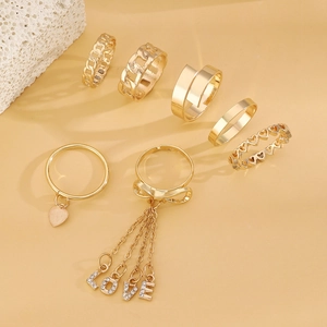 Detailed flat lay of a six-piece gold ring set featuring heart charms and crystal LOVE charms