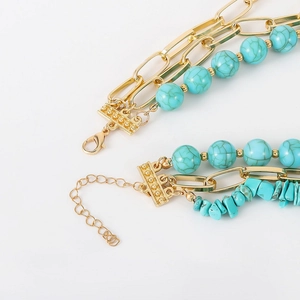 Close-up of bohemian layered gold necklace with turquoise beads and irregular natural stones