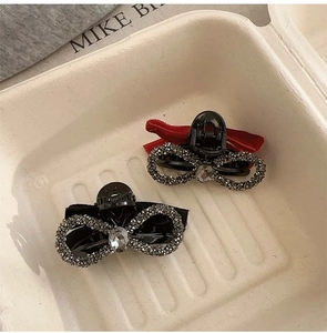 Detail view of black velvet bow hair clips with rhinestones in red and black