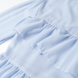 Dettaglio della camicetta azzurra con balze a strati e morbido tessuto in chiffon