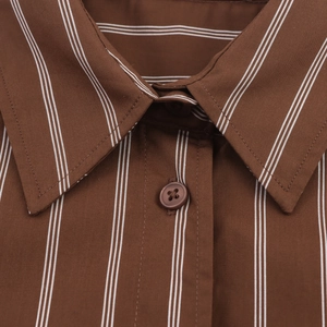 Close-up of the pointed collar and button detail on a brown striped cotton shirt