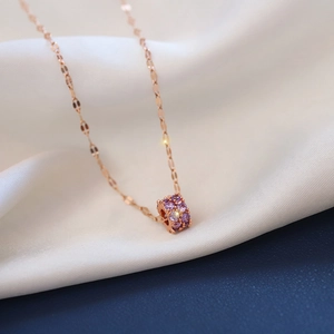 Close-up of rose gold necklace featuring a cylindrical pendant with purple zircon stones