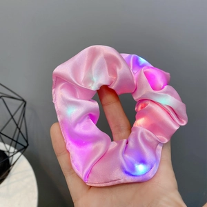 Detail of pink satin LED scrunchie showing luminous effect and silky fabric texture