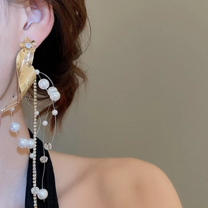 Close-up of golden tassel earring featuring pearl flowers and sparkling leaf details