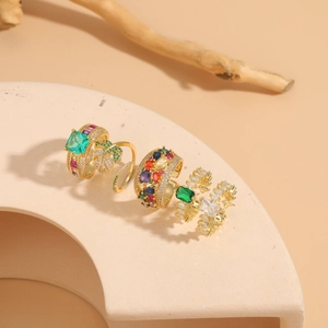 Detail of four 14K gold plated geometric rings with colorful zircon on a minimal stand