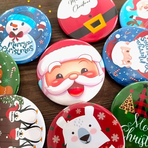 Christmas tinplate badges set featuring Santa, snowman, and tree on a festive dark wood background