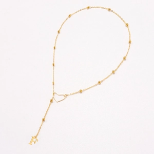 Detail of gold heart link necklace featuring small beads and letter F pendant