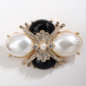 Elegant gold bow brooch with white pearls, black gems and sparkling rhinestones