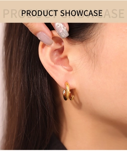 Close-up of twisted double-line gold titanium earrings worn by a model in soft lighting