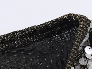 Detailaufnahme der Pailletten-Stickerei und des Metallsaums an einem Strickrock