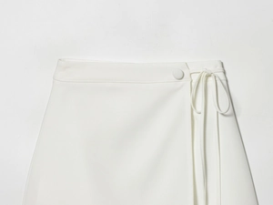 Detail of white wrap skirt waist featuring elegant side bow tie and matching button