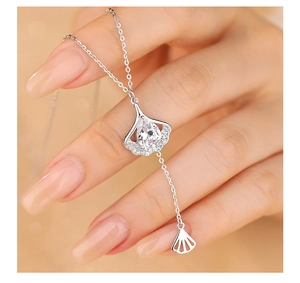 Detail of s925 silver ginkgo leaf necklace with zircon inlay and tassel charm held in hand