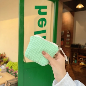 Texture détaillée d'une pochette à cosmétiques vert menthe gaufrée avec fermeture éclair