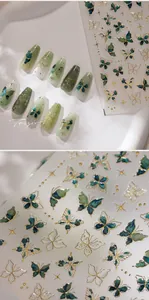 Detailed view of butterfly nail stickers with gold foil edges and emerald green accents