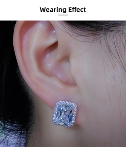 Close-up of elegant emerald-cut rectangular stud earring with sparkling diamond halo