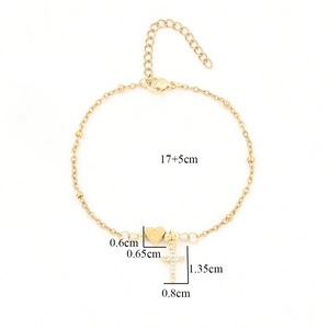 Detail of gold chain bracelet featuring letter A heart charm and crystal cross pendant