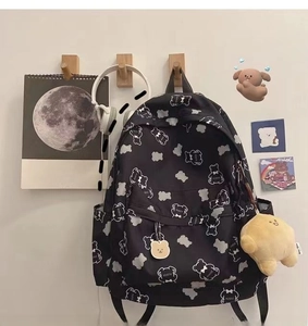 Close-up of black backpack with cute white bear print and yellow plush pendant charm