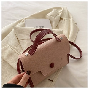 Detail of lychee textured leather and metal rivets on a two-tone mini crossbody bag