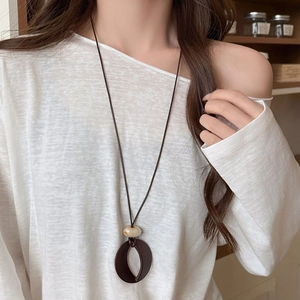 Retro acrylic resin necklace with oval pendant and marble bead on white sweater