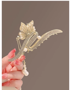 Détail macro d'une pince à cheveux papillon dorée avec perles et glands en strass