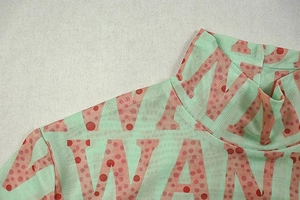 Detail of mint green mesh top with high collar and pink logo print on textured background