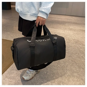 Detail of a black fitness bag showing waterproof fabric and woven handles in a lifestyle setting
