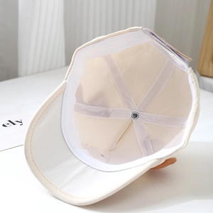 Détail de la casquette bébé beige montrant les coutures intérieures et la doublure coton