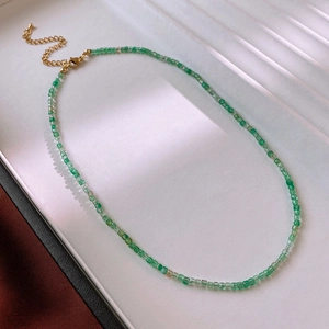 Macro shot of green bead necklace with golden lobster clasp on a textured background