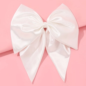 Detail of elegant white satin oversized bow hair clip with glossy texture on pink background