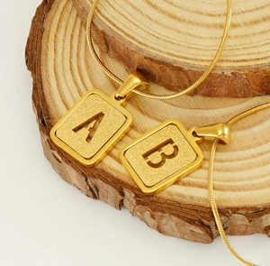 Détail du collier en acier titane doré avec pendentif alphabet et chaîne serpent