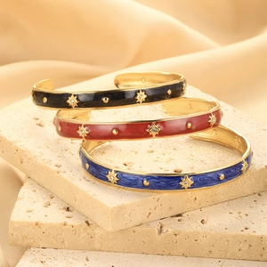 Detail of vintage enamel bangles with gold star motifs and zircon inlays on stone tiles