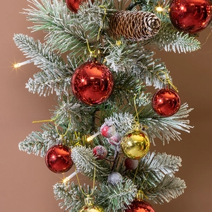 Detail of 40cm snowy pine wreath with red and gold ornaments and warm LED lights