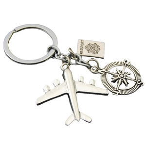 Silver metal airplane keychain with rotatable compass and passport pendant on white background