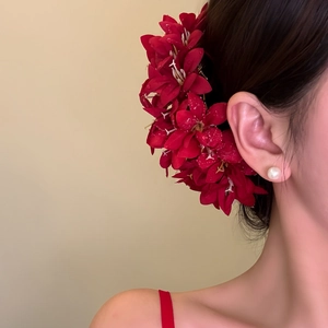 Detailed close-up showing an elegant red fabric flower hair fork worn by a model