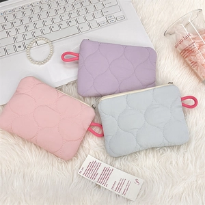 Close-up of quilted cosmetic bags in pastel colors with zippers on plush background