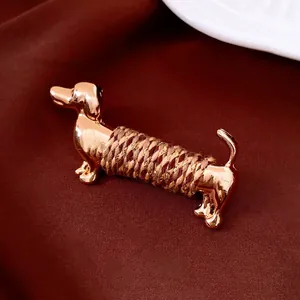 Luxury gold metal dachshund brooch featuring brown braided rope on dark silk background