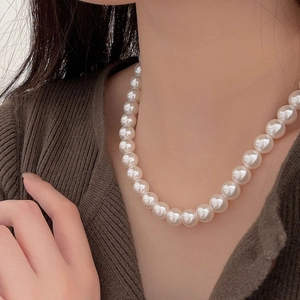 Elegant 925 silver necklace with 10mm round white pearls worn by a model on a knit top