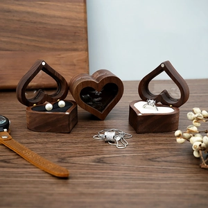 Close-up of heart-shaped walnut wood ring box with a transparent window on wooden table