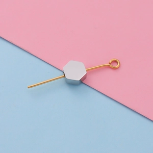 Close-up of hexagonal steel spacer bead on a golden pin for DIY jewelry making
