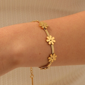 Gold daisy flower charm bracelet with sleek blade chain on a person's wrist