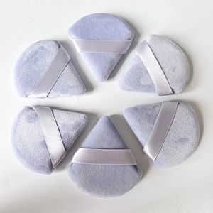 Close-up of 6 soft lavender triangular powder puffs with ribbon handles in circular layout
