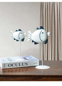 Dettaglio di pesci decorativi in legno bianco con pinne blu su supporto in metallo