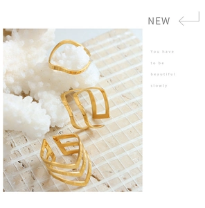Three gold geometric rings featuring minimalist wavy and V-shaped designs on coral decor