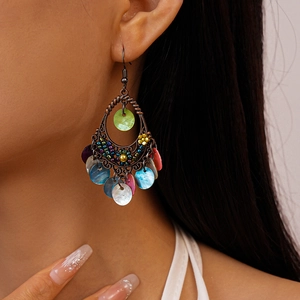Detail of bohemian drop earrings with colorful shells and bronze metal thread work